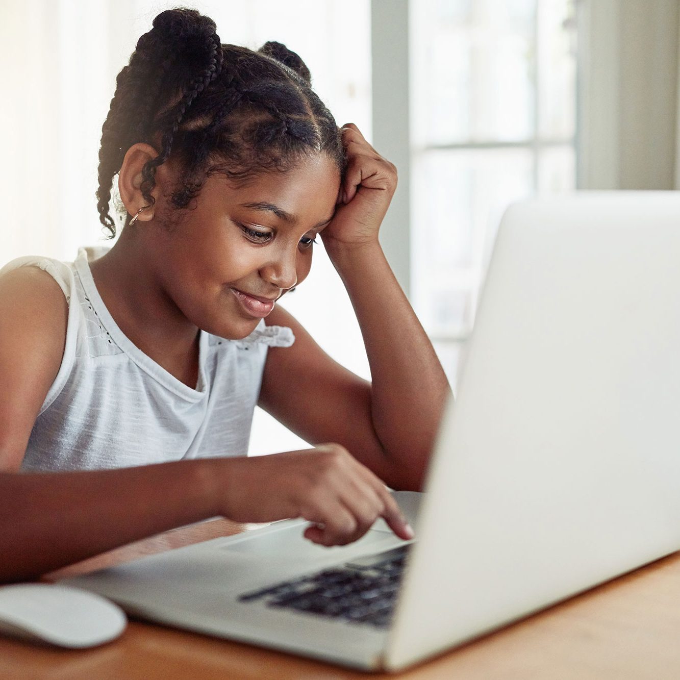 An African-American student works at her white laptop computer.