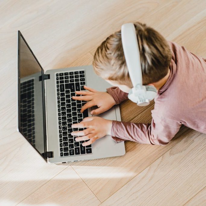 Boy typing on laptop with headphones